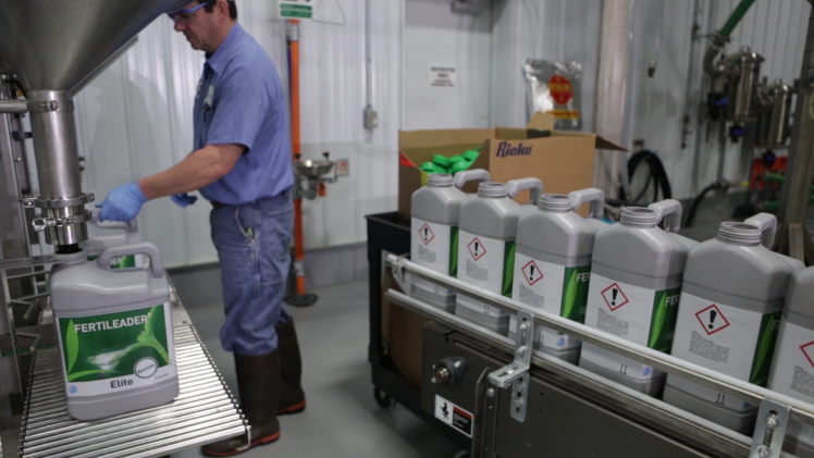 Industrial employee filling FERTILEADER jugs in the biostimulant plant in the Reading unit.